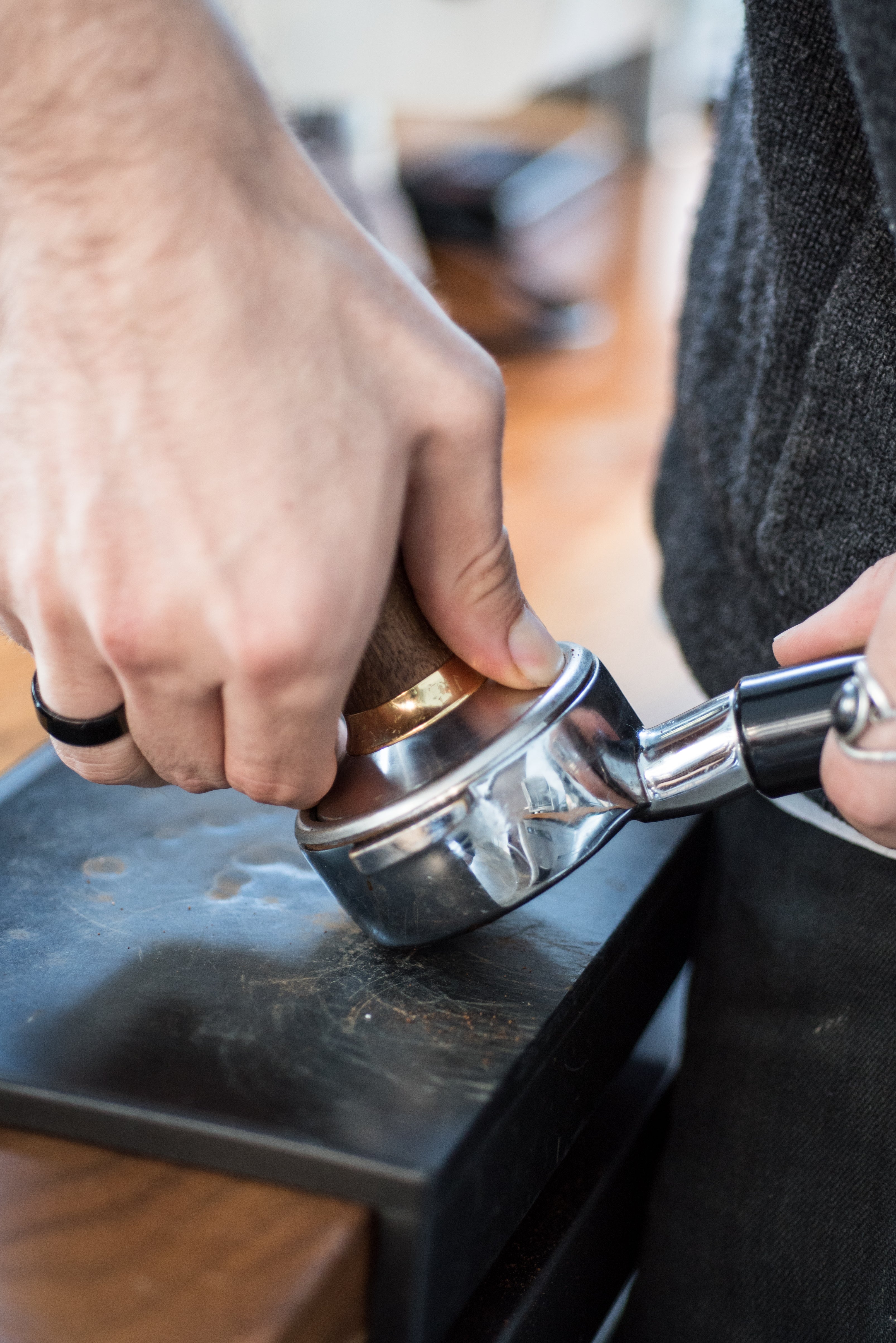 Person using a metal tamp to compress coffee grounds in a portafilter in the Coffee Cart